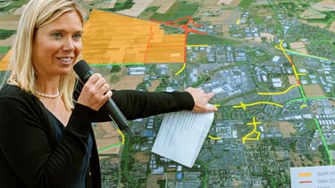 Speaker pointing at map with funding projects outlined