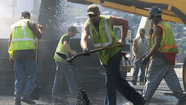 Construction workers shoveling asphalt