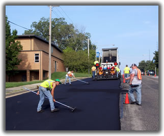 a highway maintenance crew smoothing a newly paved road