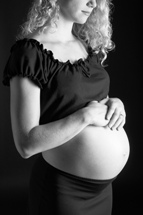 black and white portrait of pregnant woman with her hands resting on her abdomen
