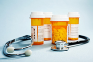 Four prescription medication bottles containing pills and a stethoscope
