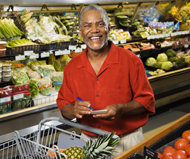 Smiling man pushing shopping cart in the produce aisle of a grocery store