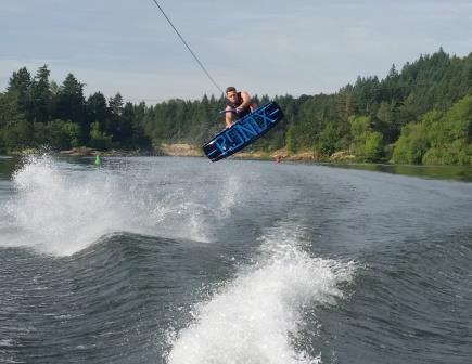 Picture of a wakeboarder catching air over a boat's wake