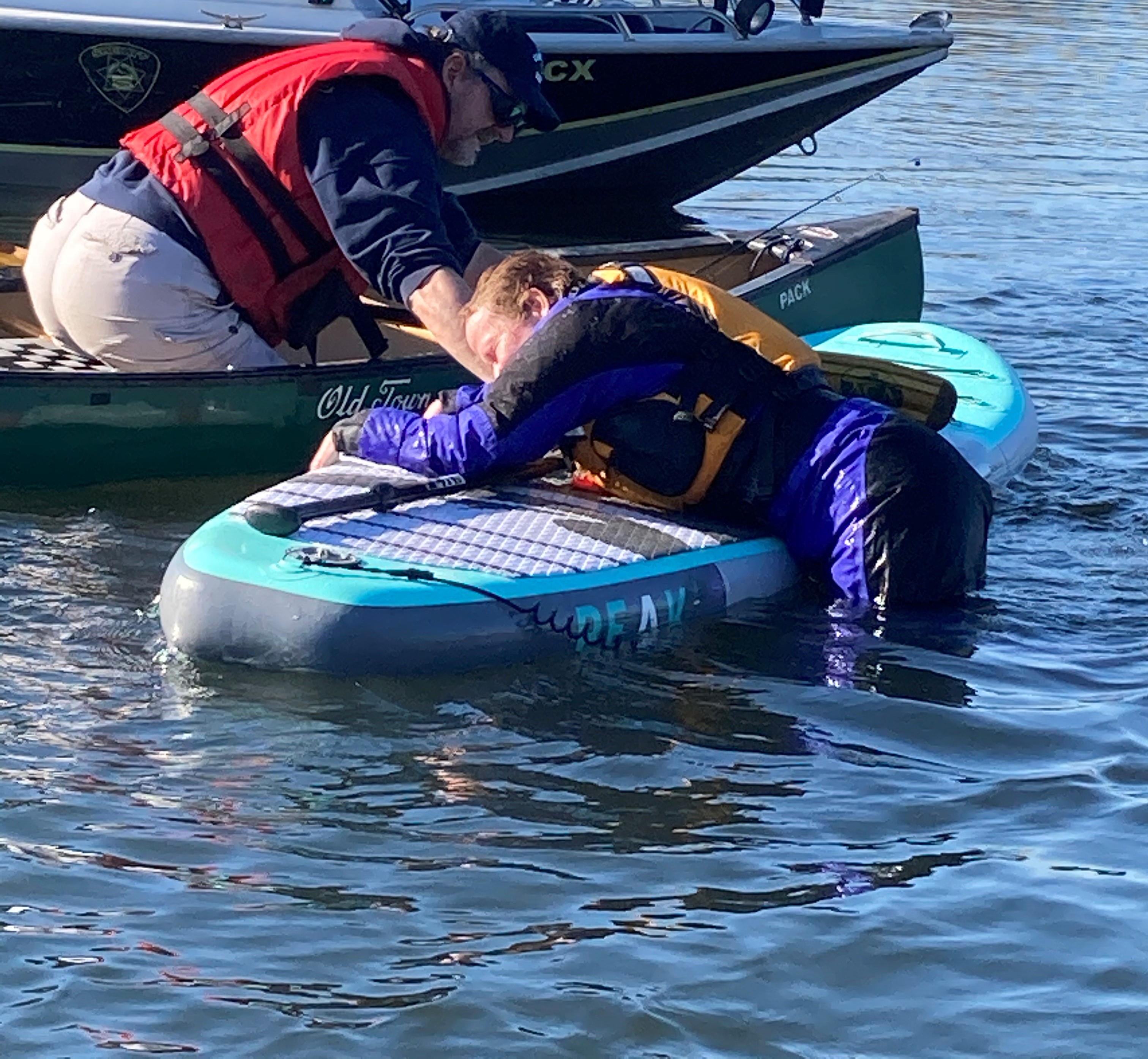 Care -Canoeist helping a paddleboarder get back on the board