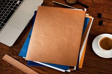 Laptop and file folders on a desk.
