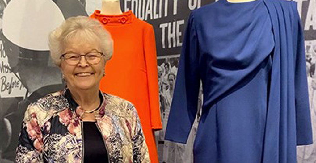 Former governor Barbar Roberts standing in front of her blue dress on display
