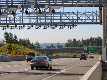 A photo shows a car driving underneath a toll gantry.