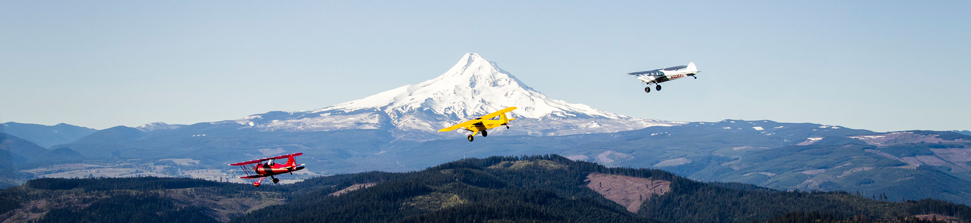 three planes flying infront of a mountain range