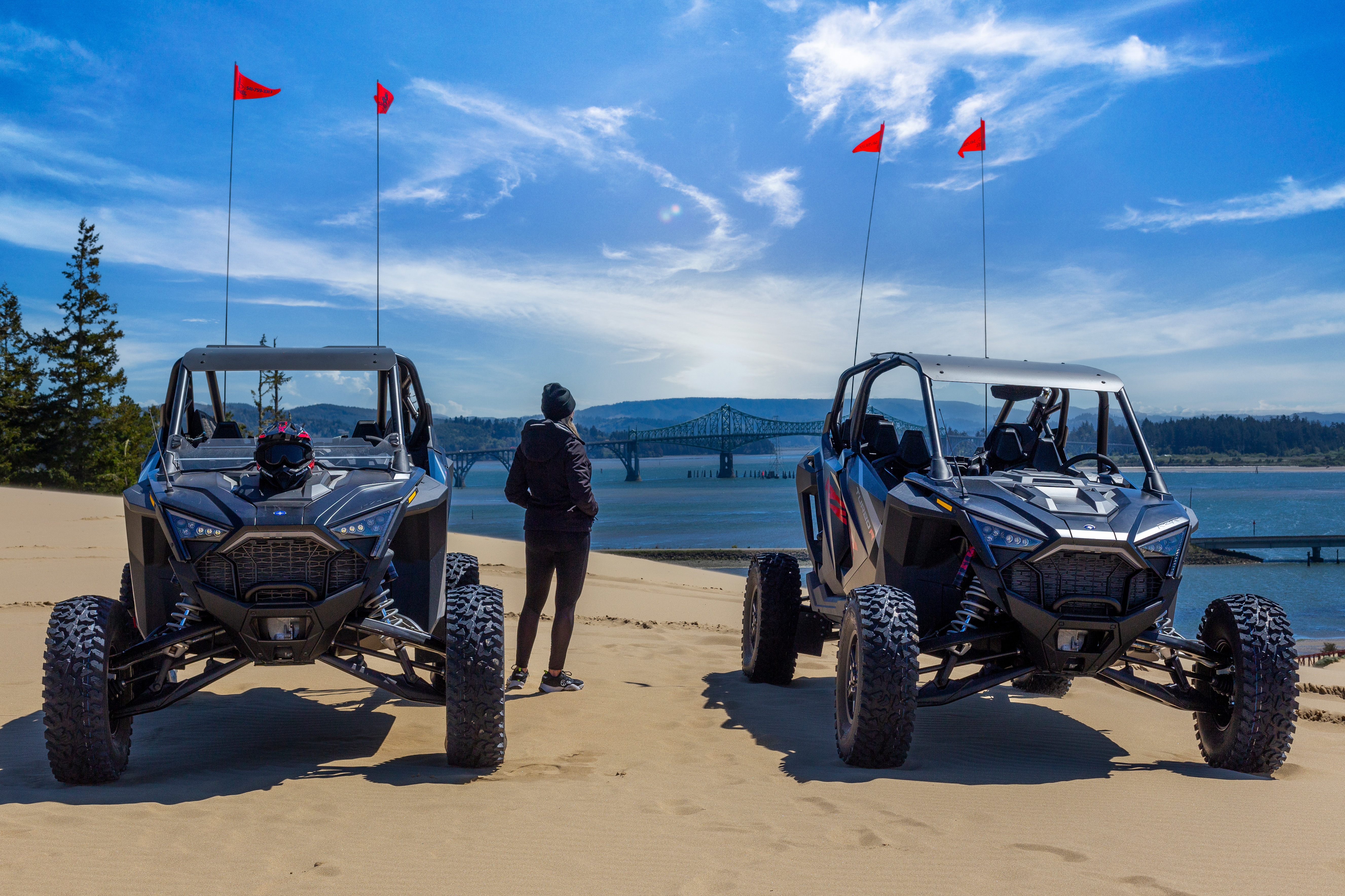 Person standing next to ATVs on the beach sand