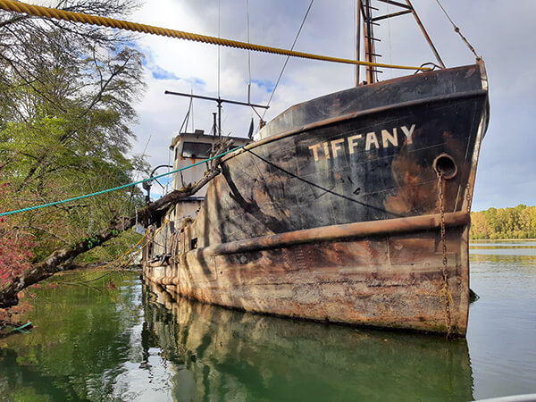 Large rusted military vessel with the name Tiffany on the side.