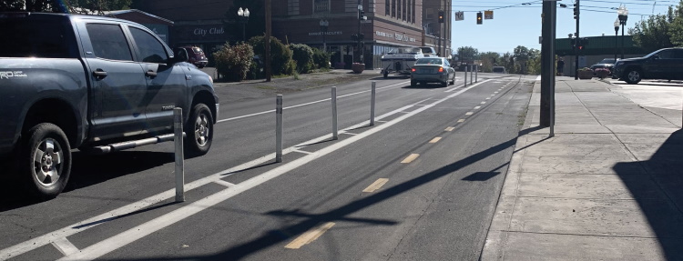 Two-way protected bike lane adjacent to cars approaching a yellow light