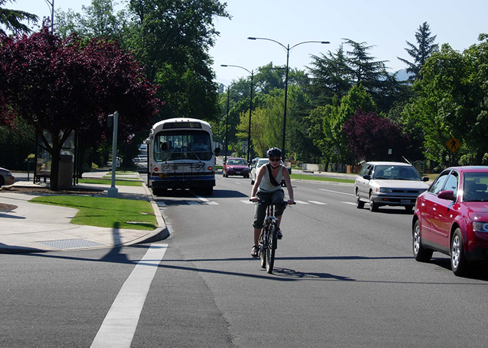 A biker, cars, and bus all share the road in Ashland.