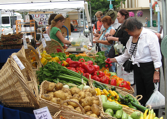 A woman selects fresh produce from a farmers market stand