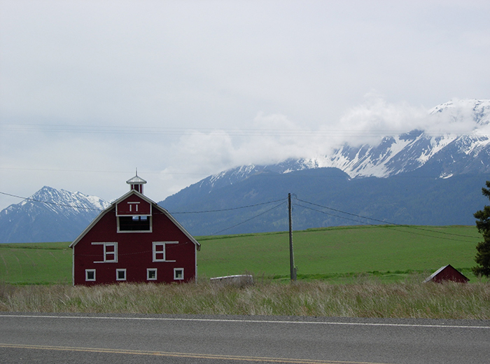 Red barn in front of mountains.