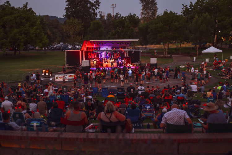 Crowded amphitheater full of people with band playing on a stage