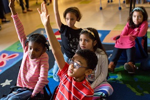 Young students raising their hands to answer a question