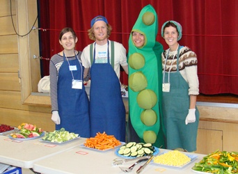 Four farmers serving vegetables with one dressed in a peapod costume