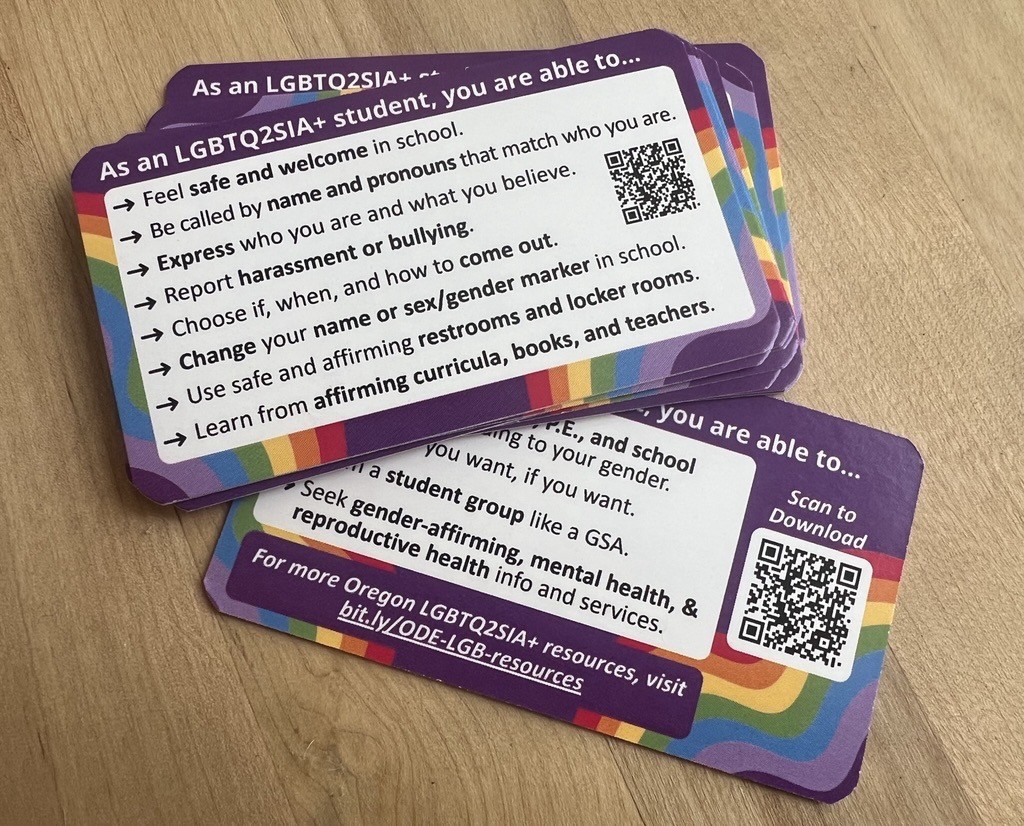 Stack of purple, white, and rainbow colored cards outlining supportive actions for LGBTQ2SIA+ studenst in Oregon public schools.