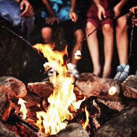 Roasting marshmellows around campfire.