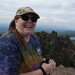 Photo of Christie, a woman with long red/brown hair that is in a ponytail. 