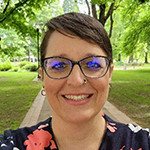Photo of Erin, a woman with short brown hair and glasses. She is smiling at the camera.