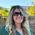 Photo of Marissa, a woman with long blonde hair. She is wearing a green v-neck button-up short sleeve blouse. 