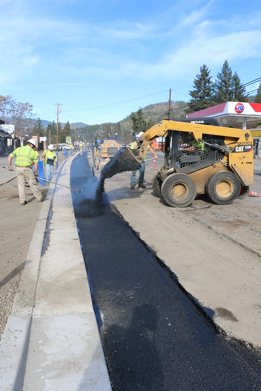 Photo of ODOT workers pouring fresh pavement next to a sidewalk.