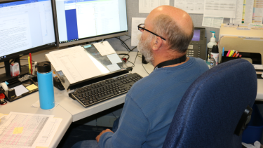 Employee sitting in front of a computer looking at the computer screen