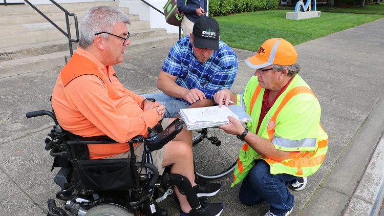 Team providing support on ADA curb ramp program with two idividuals on wheelchair