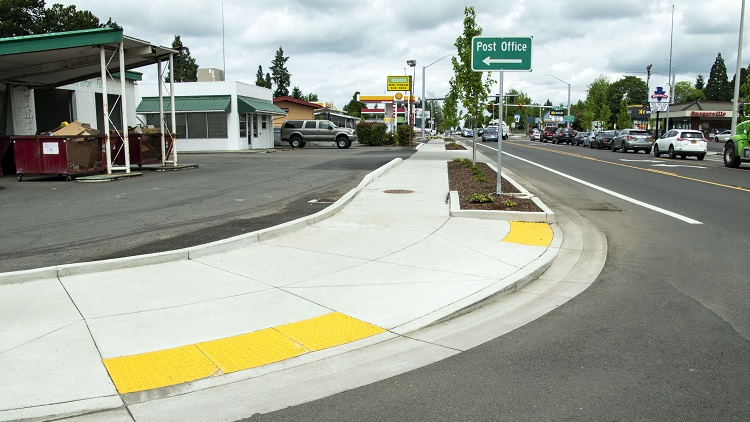 Completed ada curb ramp with tactile strip at the corner of an intersection in Oregon.
