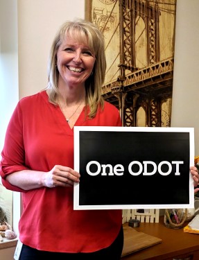 Employee standing and holding a sign that reads "One ODOT"
