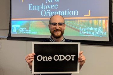 Employee holding a sign that reads, "One ODOT."