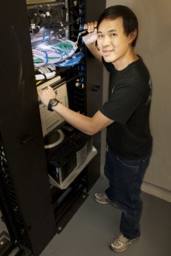 Employee standing in front of a server box full of wires