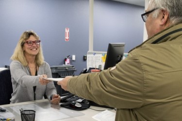 DMV employee handing paperwork to a customer