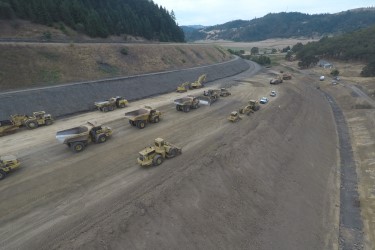 A crew of highway tractors and trucks working on a new road.
