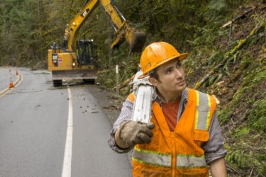 Highway maintenance specialist holding a saw on his shoulder.