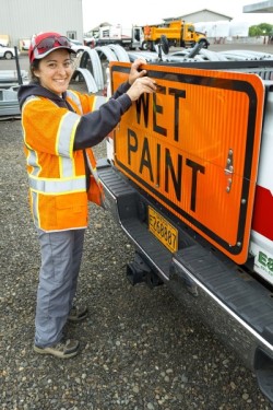 HIghway employee standing in front of a wet paint sign.