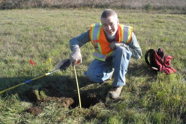Geoenvironmental employee measuring the depth of a hole in the ground