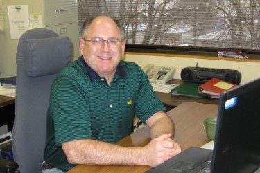 Employee sitting at an office desk and smiling at the camera