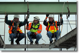 Bridge inspectors in hard hats and orange vests inspector a metal beam