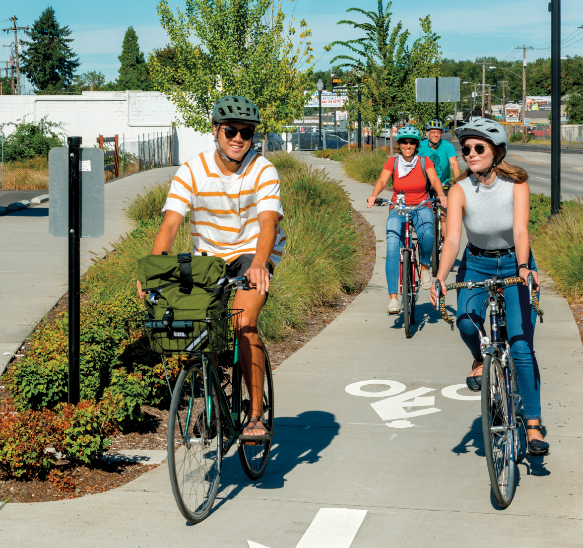 Image - four people riding bicycles along a marked bicycle path..