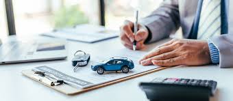 man writing on desk with model car and keys
