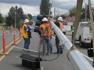 Crews works to mount a new traffic signal to the mast arm