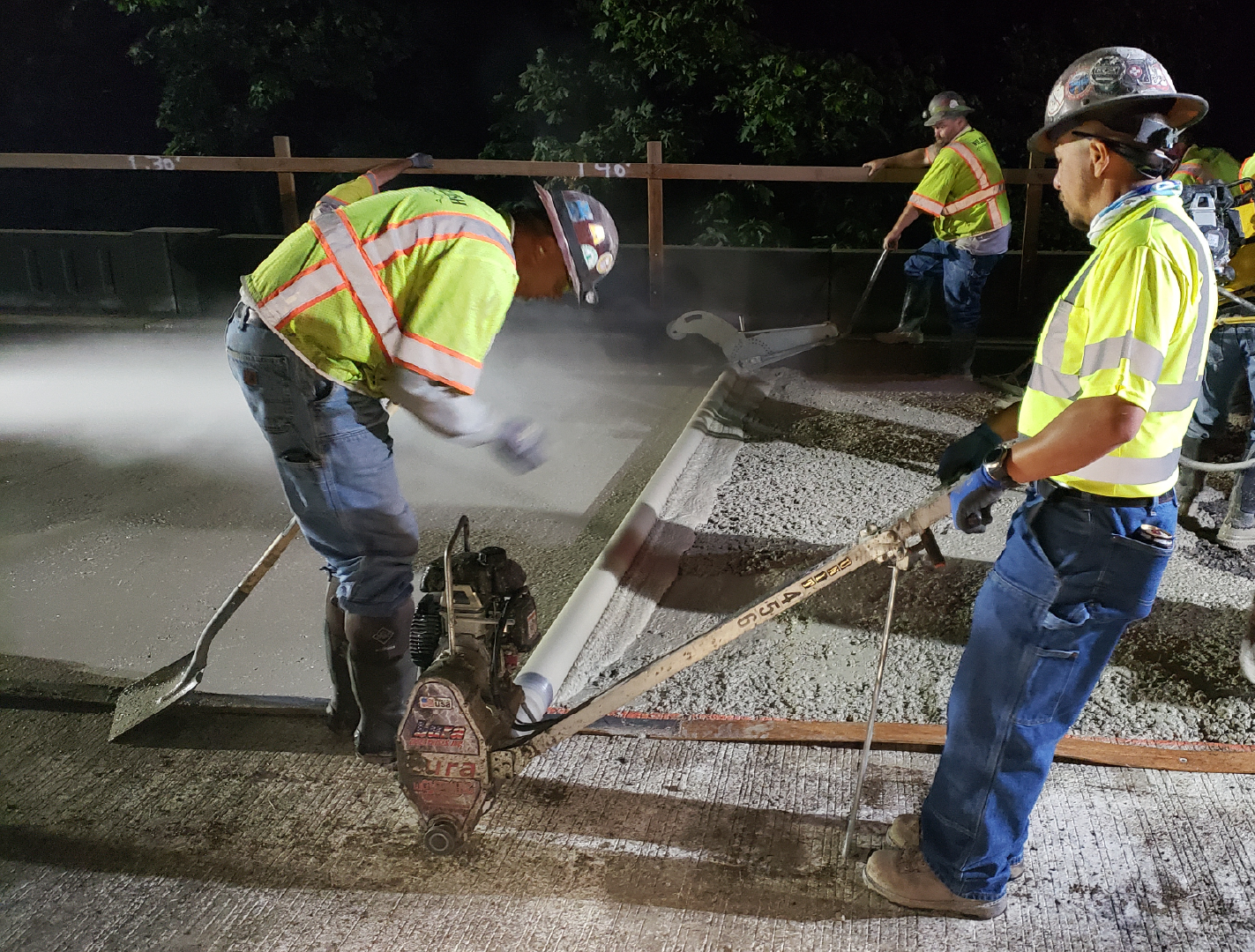 Photo showing crews install concrete on a bridge driving surface