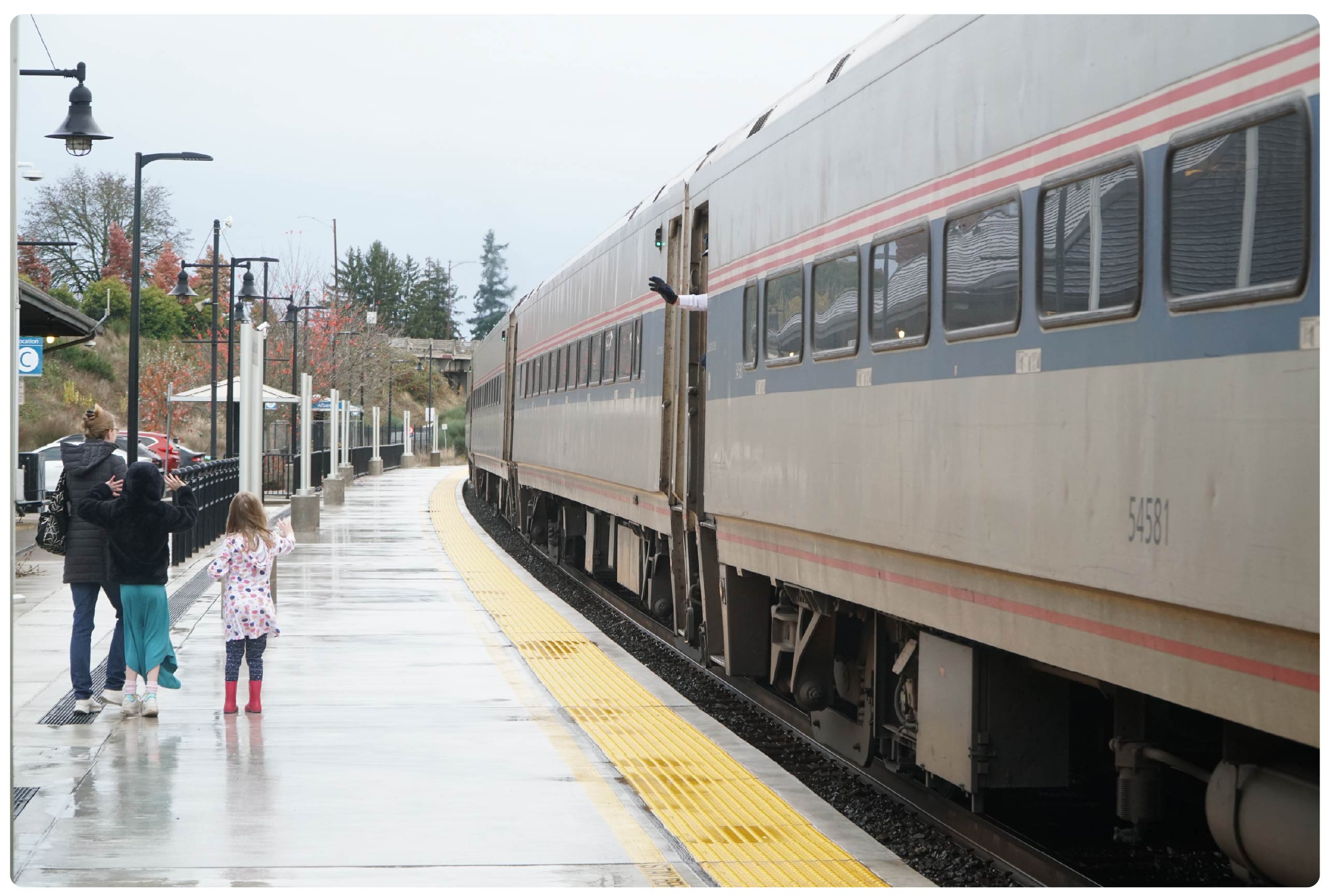Photo of a train at the station with a family waving goodbye