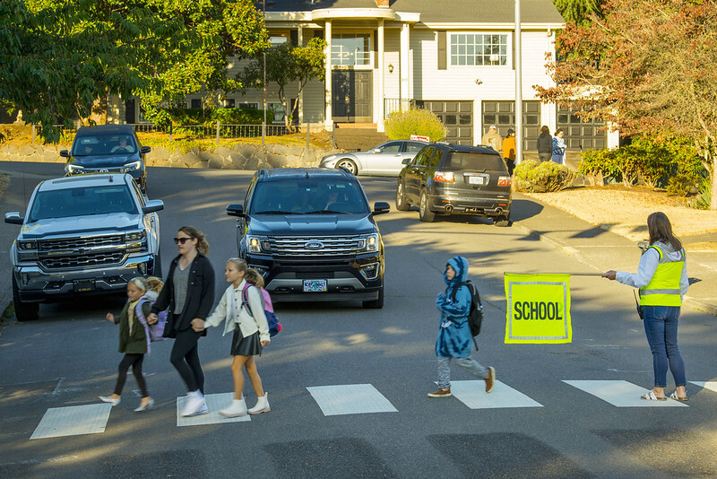Children crossing the street in a school zone with a crossing guard