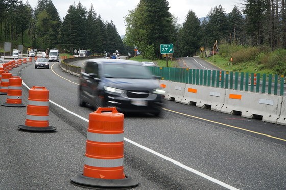 A photo of cars moving through a work zone with a concrete barrier and oranges barrels