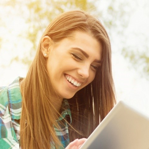 Young woman with big smile looking at laptop