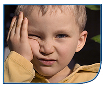 boy holding his face and squinting as if in pain from a cold or headache