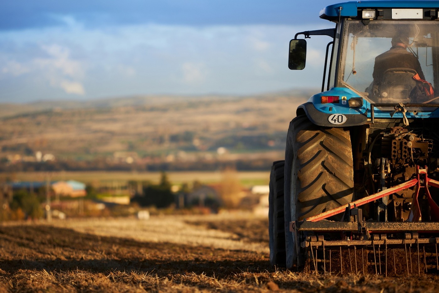 A farmer tilling their field on a tractor.